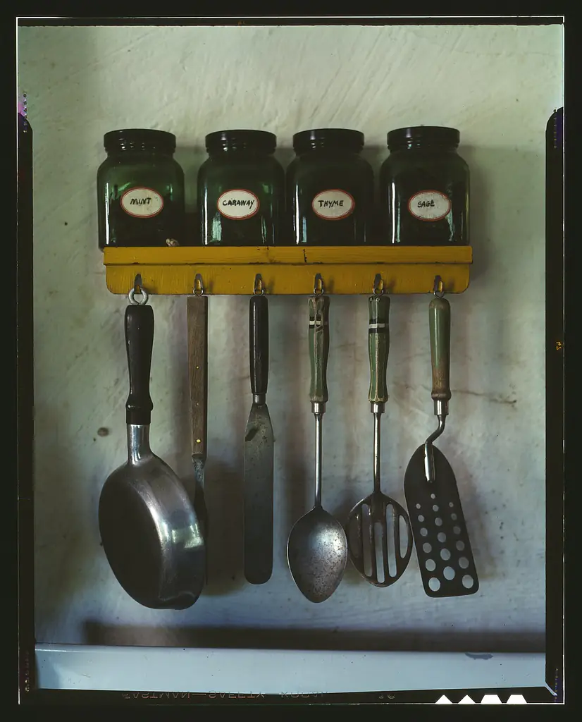 Kitchen utensils hanging below a spice rack 1a35478v