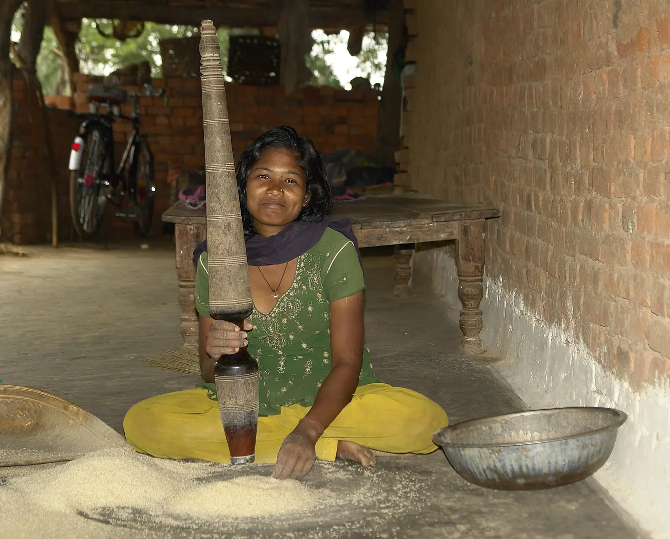 Young adivasi woman crushing rice, MP, India